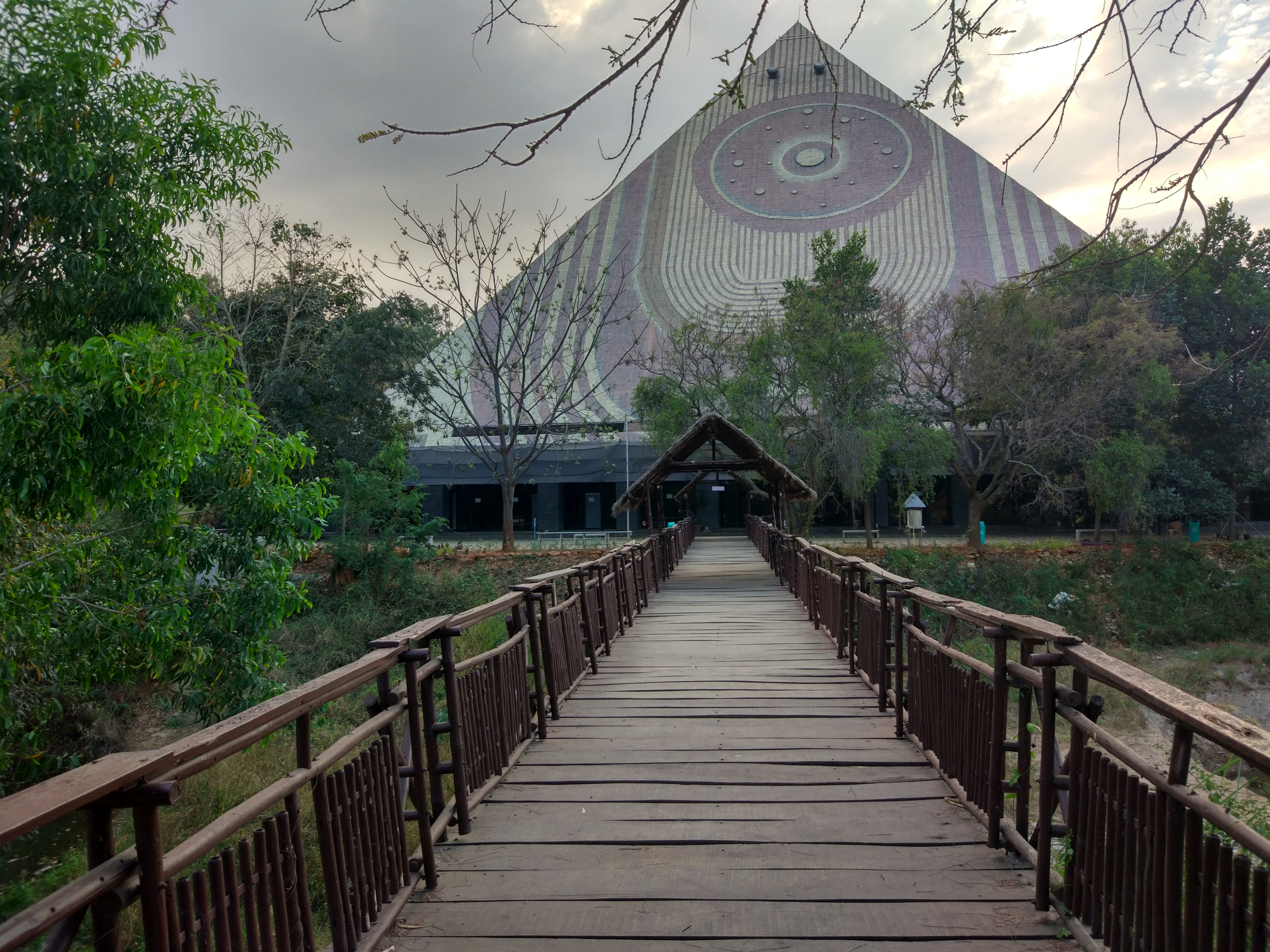 Wooden footbridge leading to the Maitreya Buddha Pyramid through the valley trees