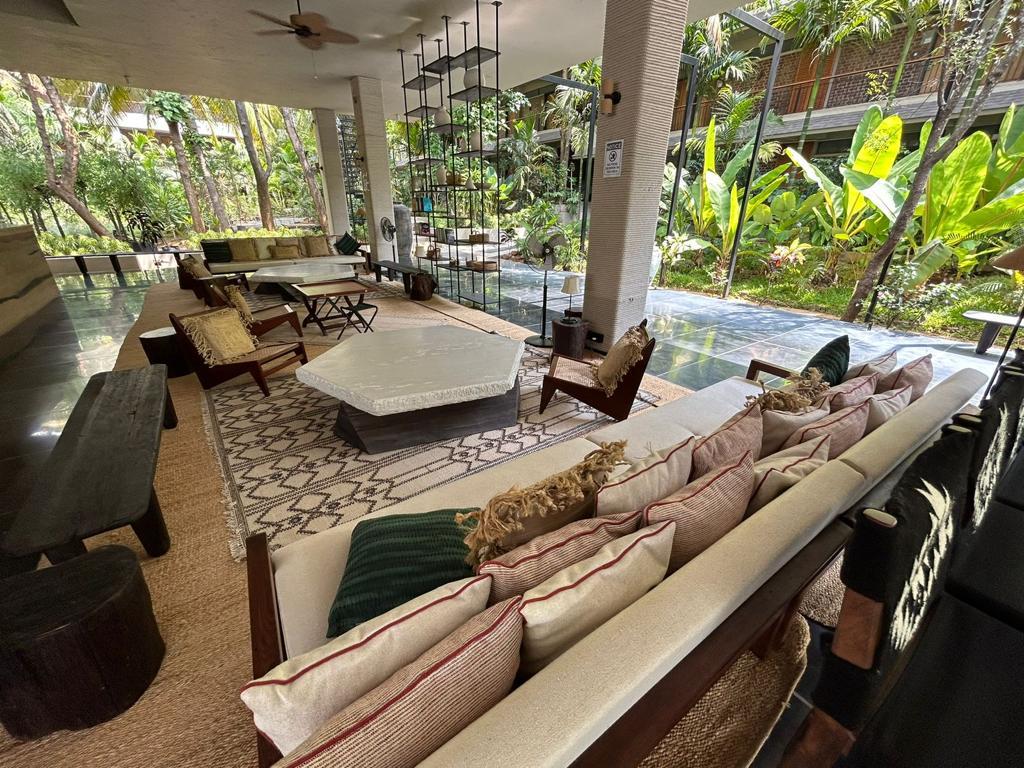 Open-air lounge with stone-topped tables, woven seating, and garden views