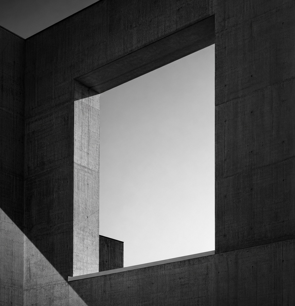 Sunlight through a raw concrete facade opening onto trees