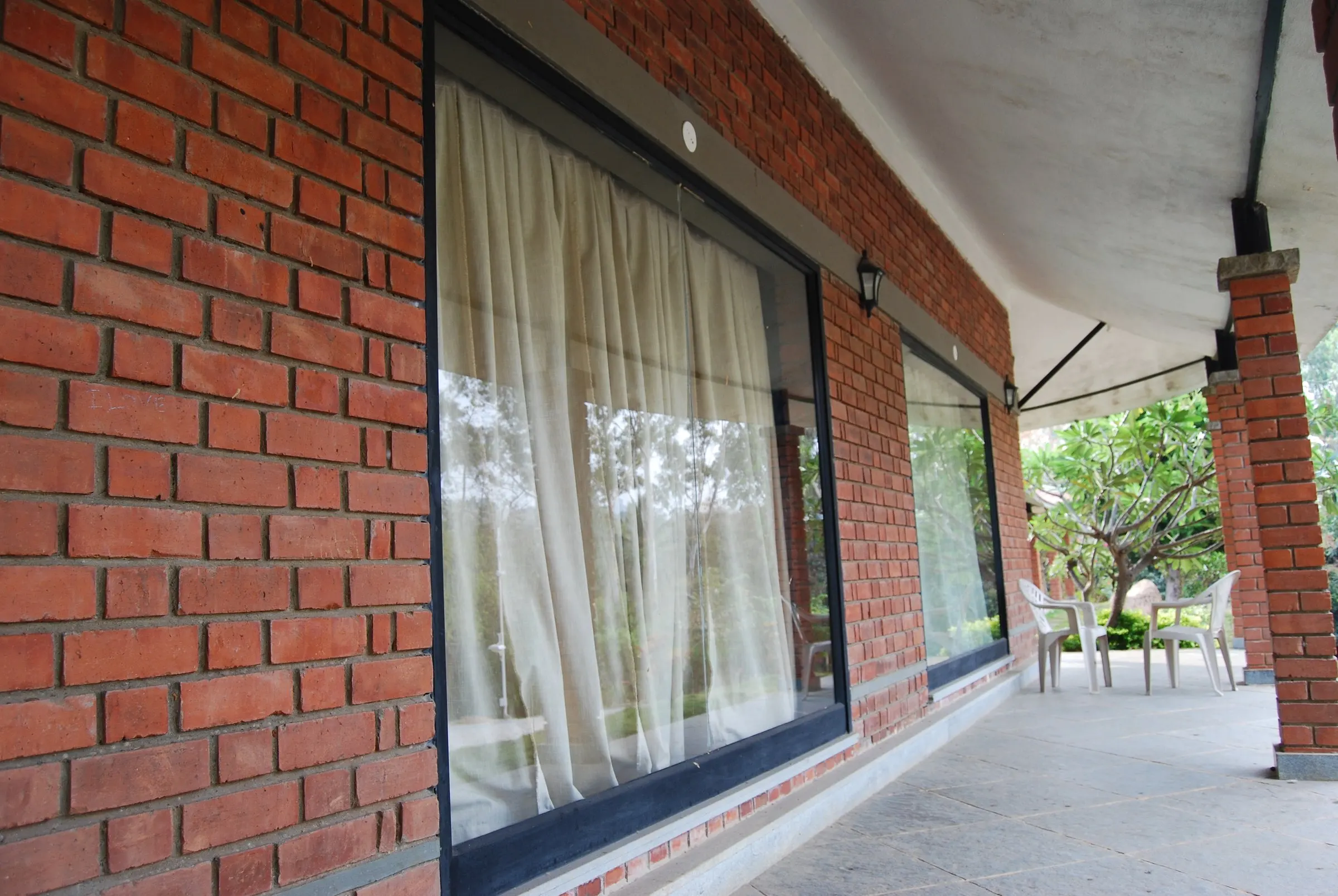 Exposed brick and a full-height window beneath a deep verandah