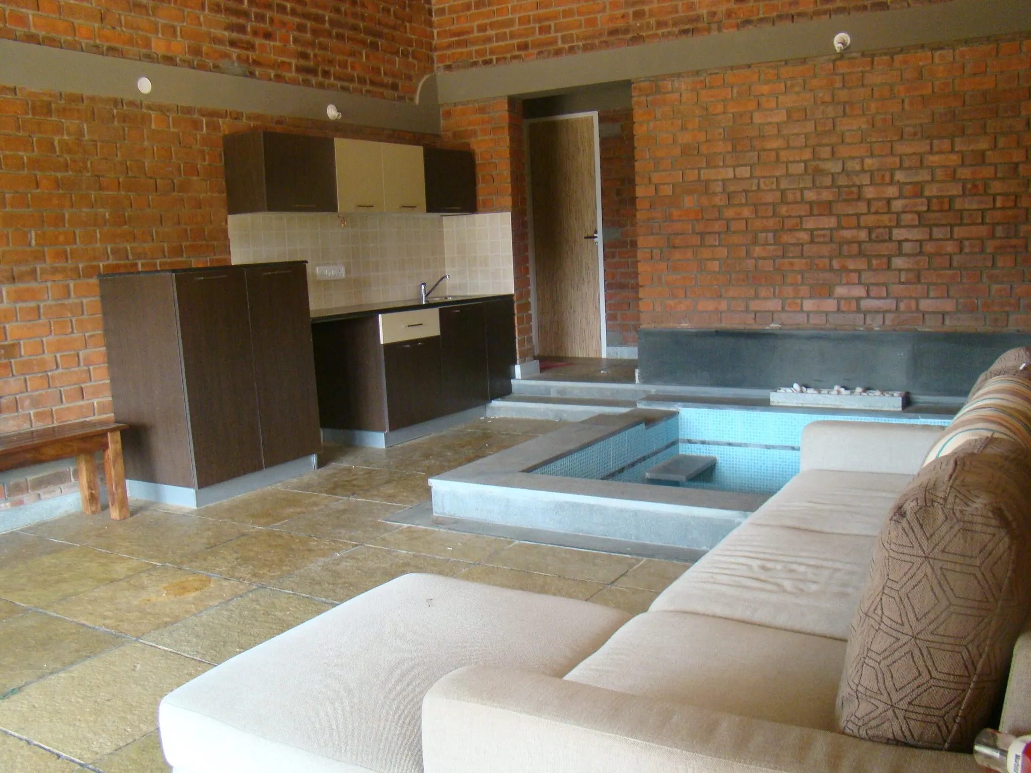 Inside a cottage: exposed brick, a stone floor and a low water basin