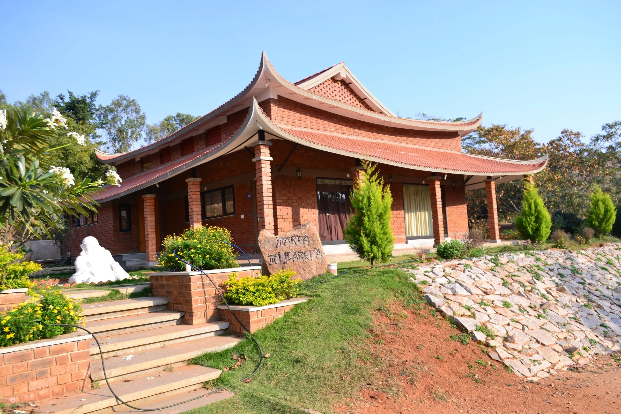 A pagoda-roofed cottage with stone steps and flowering shrubs