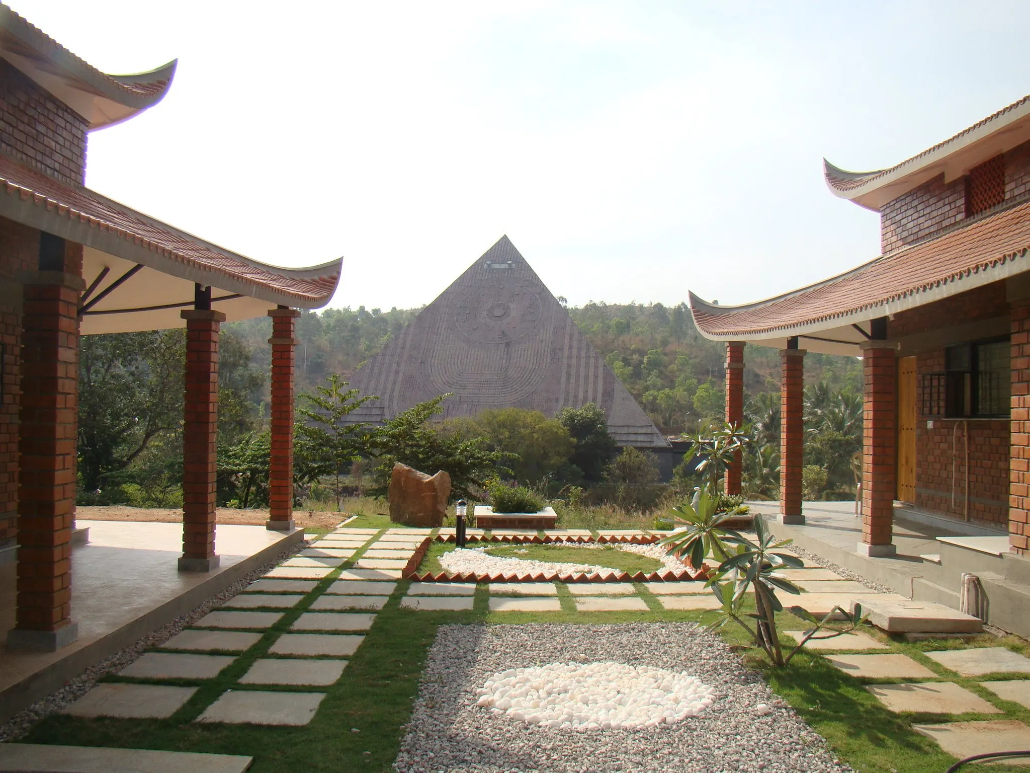 The court between two cottages: stepping stones, white pebbles and the pyramid beyond