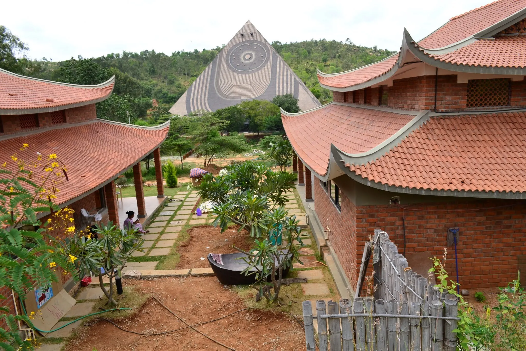 Curved terracotta pagoda roofs of the cottages framing the spiral-patterned meditation pyramid beyond