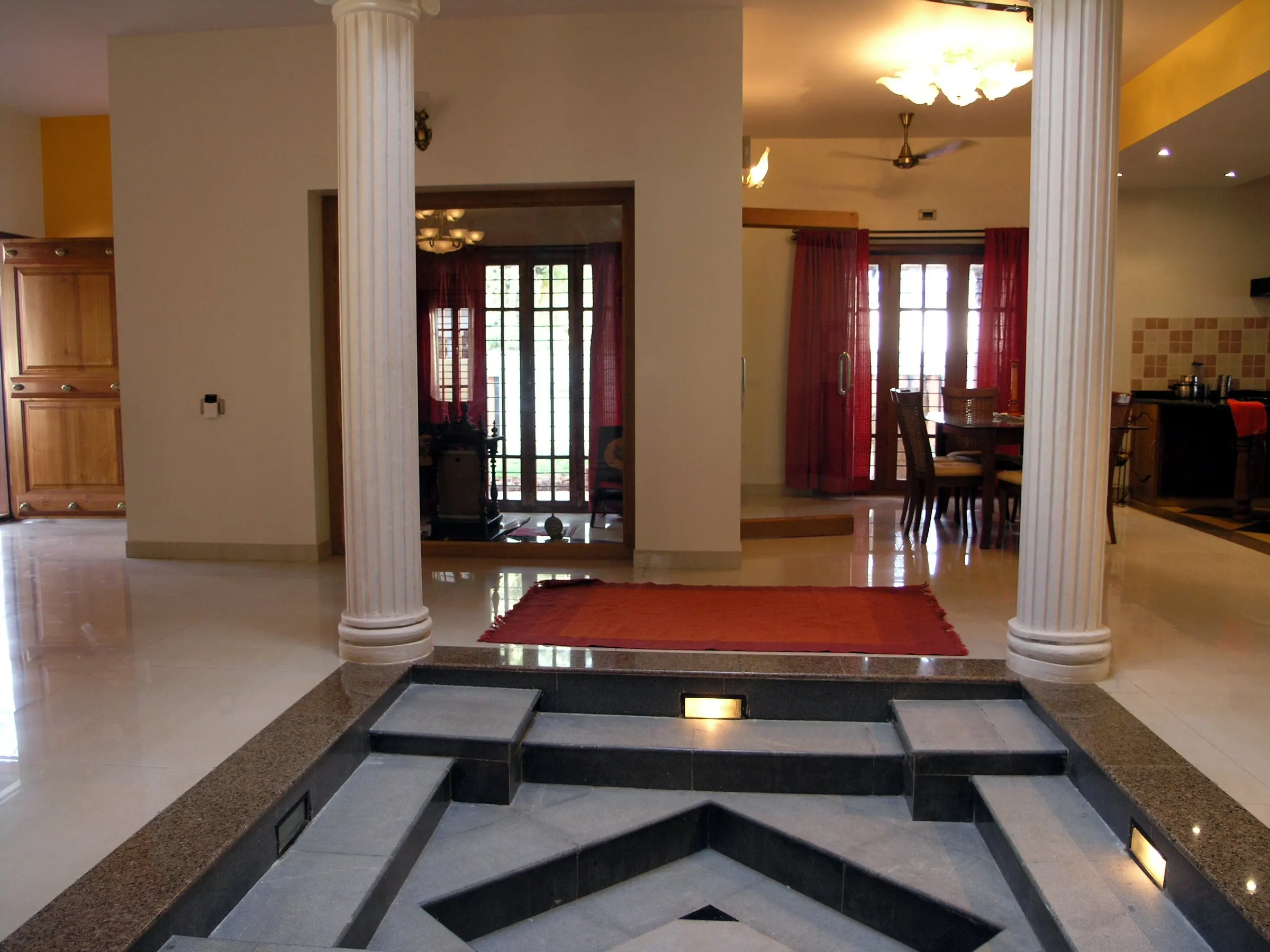 A hall with white columns and a stepped granite feature set into the floor