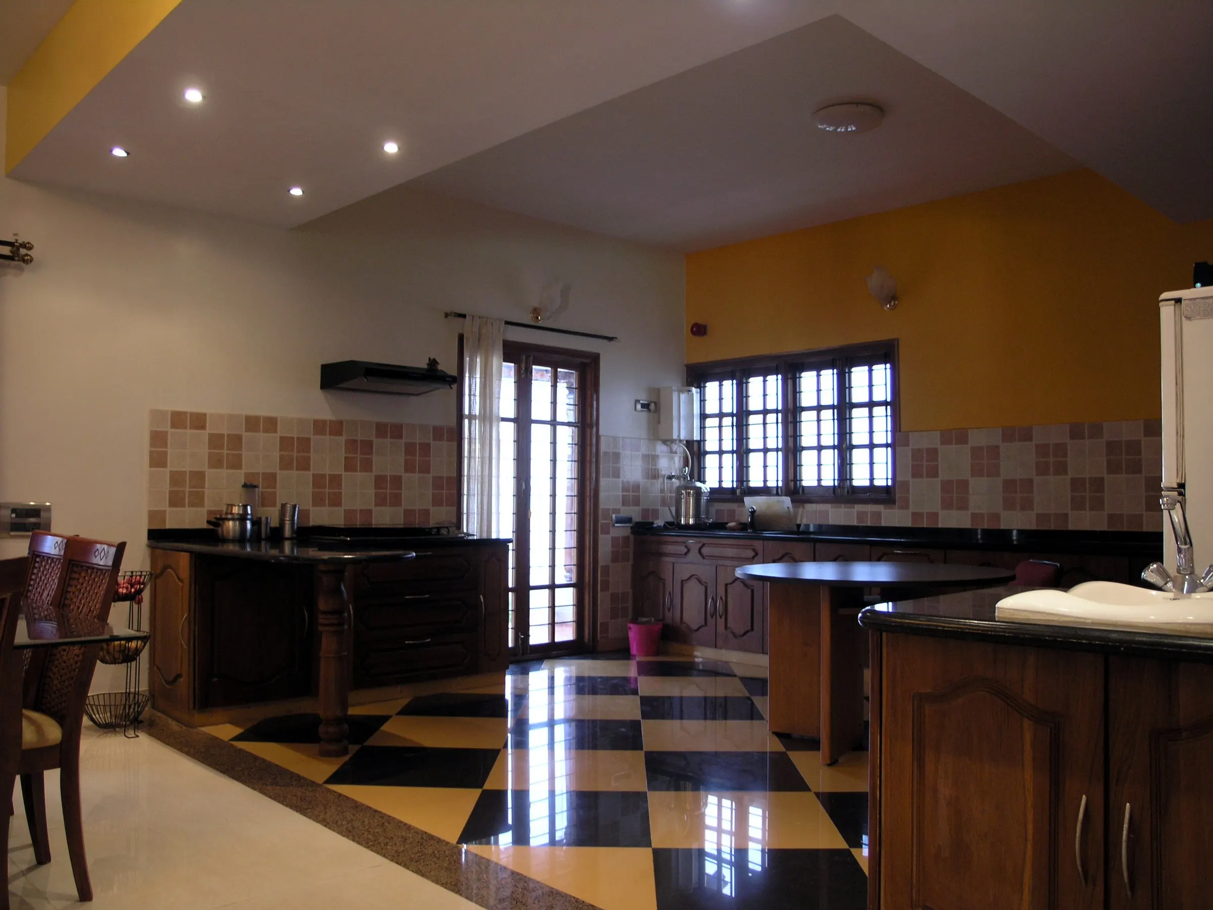 A kitchen with a black-and-white chequered floor and warm yellow walls