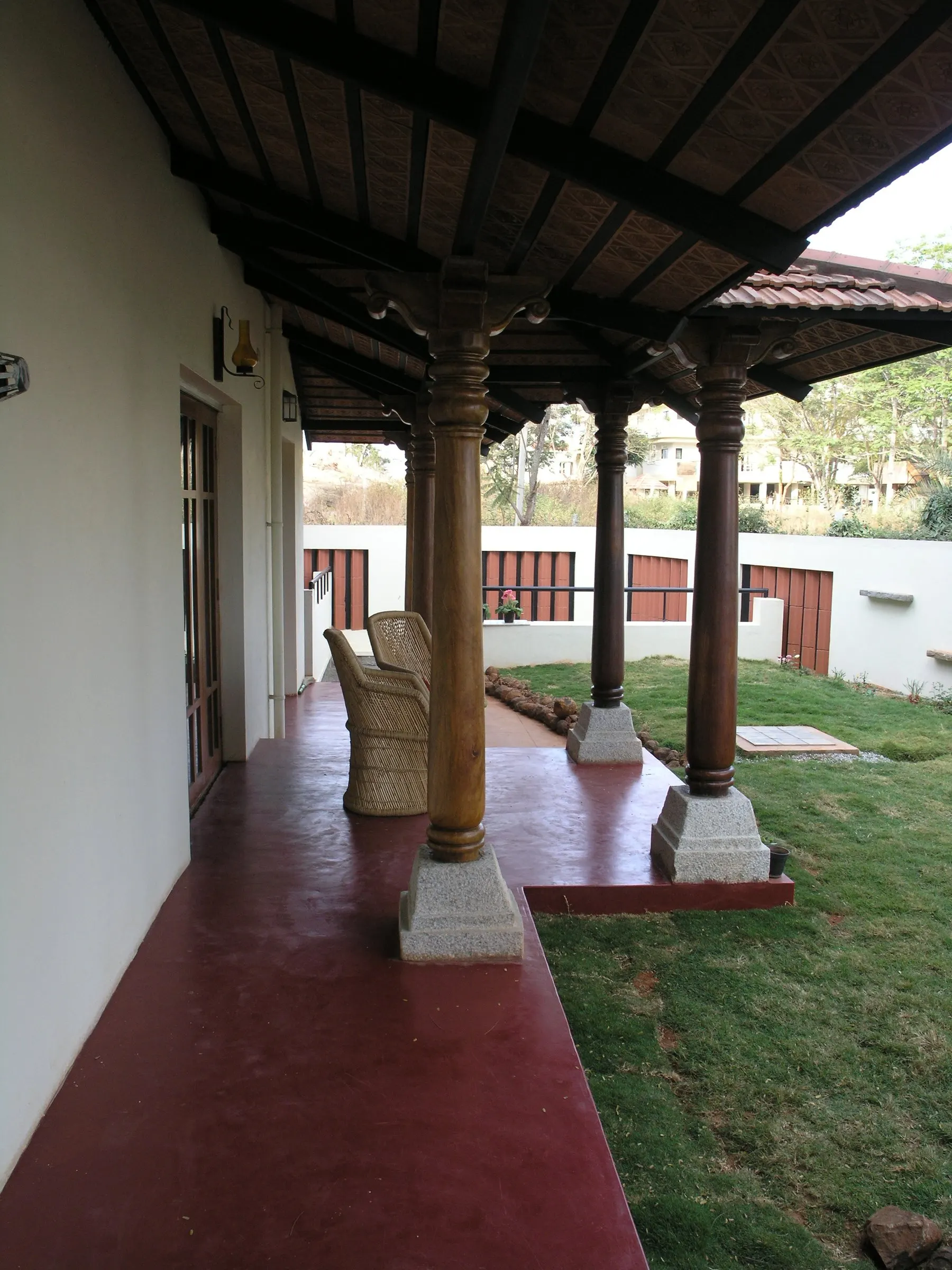 The verandah running along a lawn beneath a timber-beamed roof