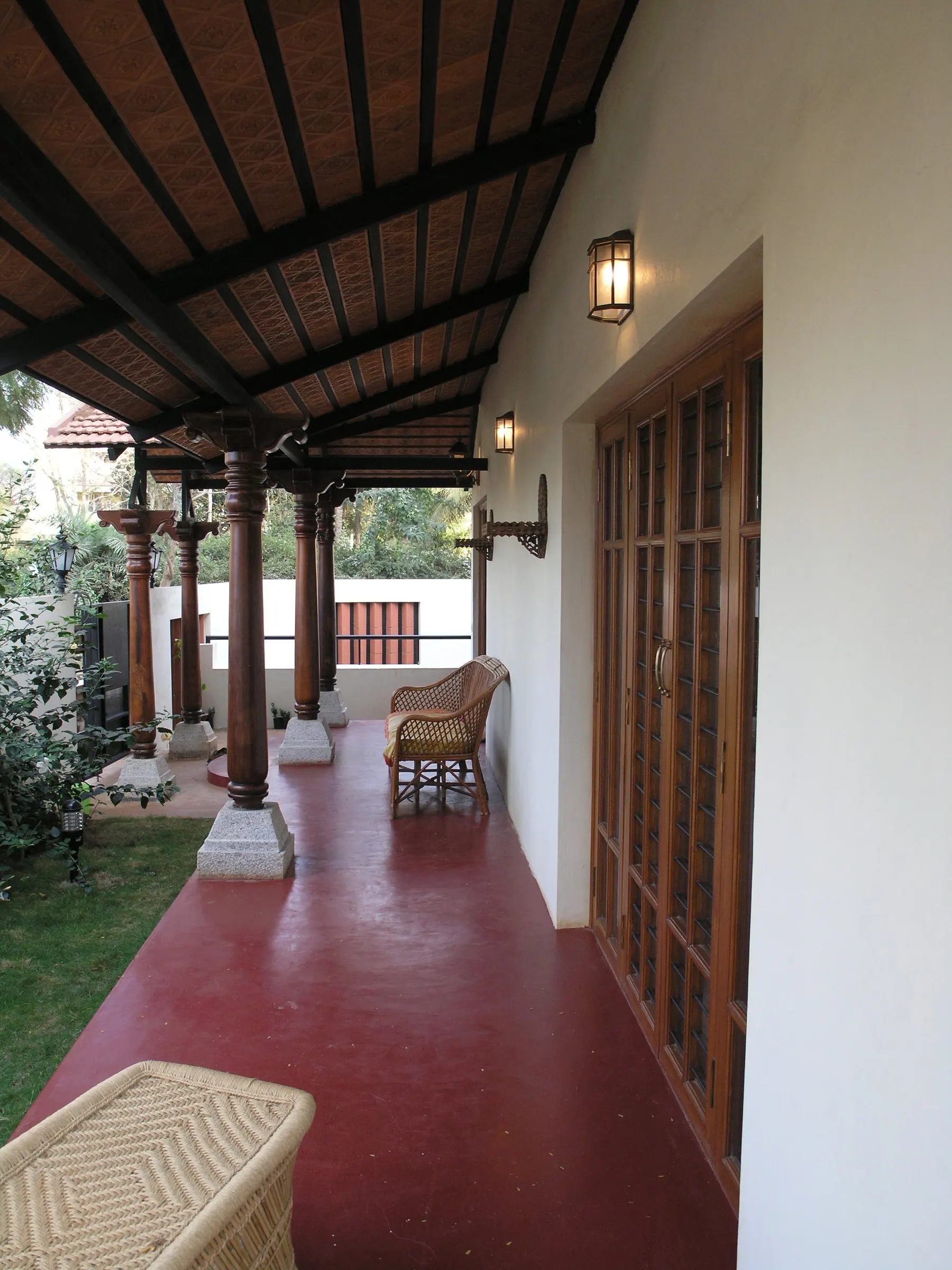 A deep verandah with timber columns on white bases and a red-oxide floor