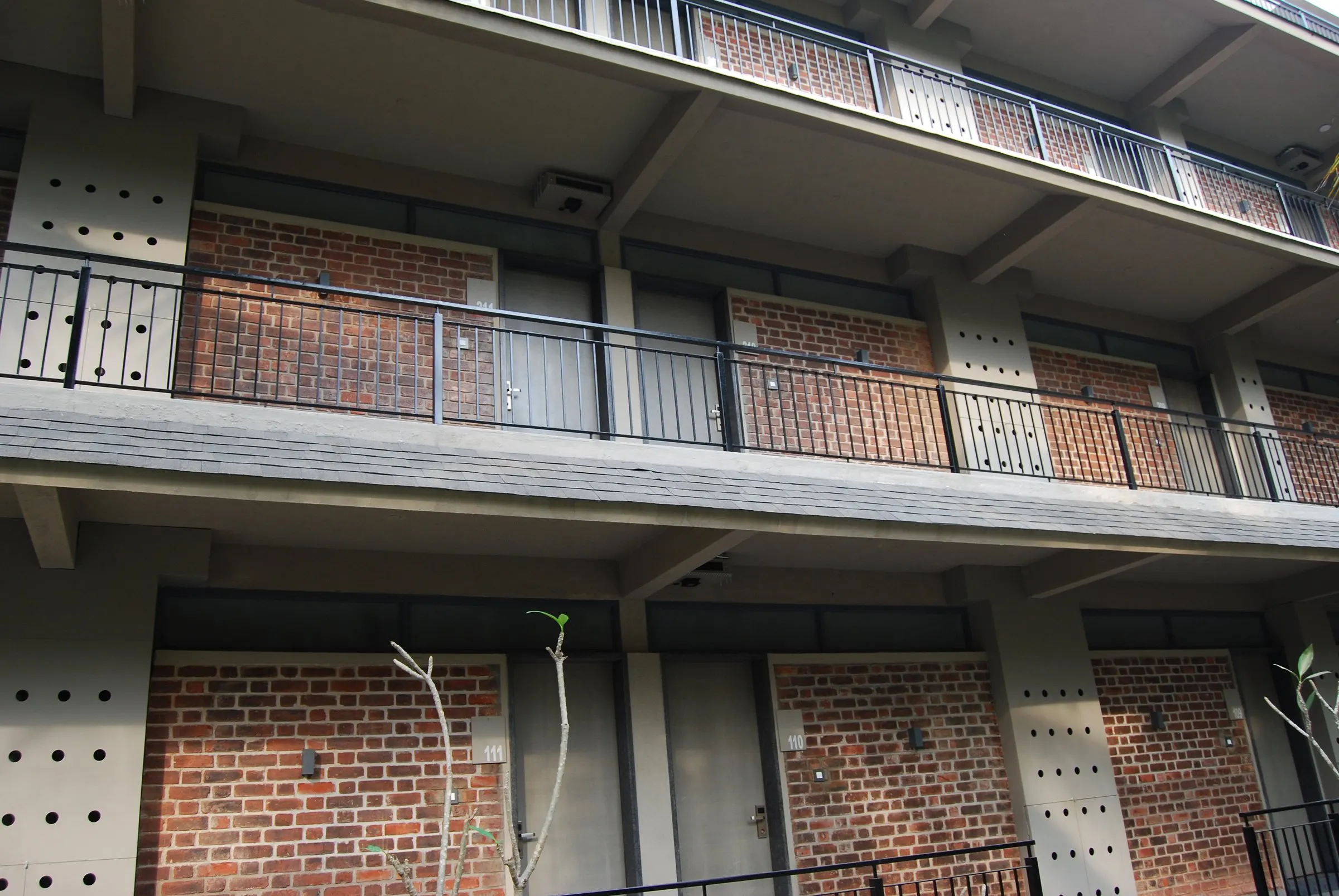 Concrete slabs and brick infill on the balconies of a three-storey block
